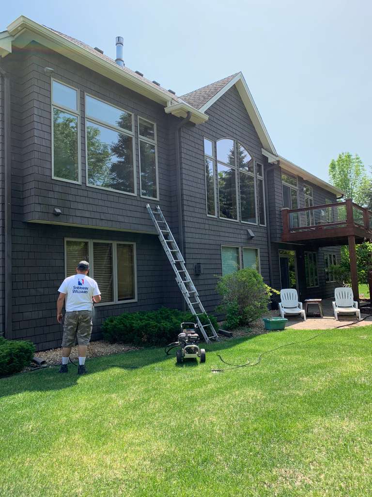 Team painting dark wood siding home